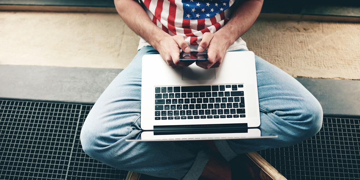 Man in American flag shirt on his laptop.